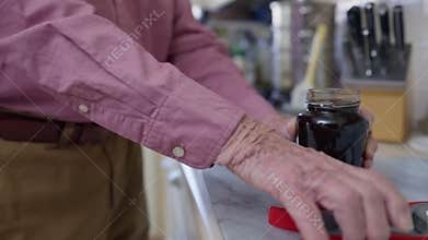 Senior Man Taking Lid Off Jar With Kitchen Aid
