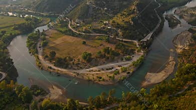 aerial scenic landscape with green fields, meadows, curved mountain river and mountain ridge with high mountains and