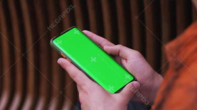 Close-up of a Man Holding Green Mock-up Screen Smartphone and Using Touchscreen Gestures. Touching Mobile Phone Chroma