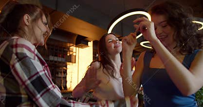 Dance Extravaganza: Three Joyful Girls Grooving at a Sunlit Cafe-Bar Bachelorette Party