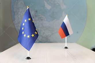 Political flags of russia and European Union on table in international negotiation room. concept of negotiations, collaboration