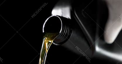 worker pouring car engine oil from bottle on black background. motor maintenance