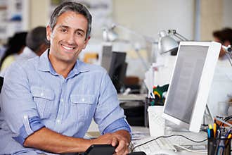 Man Working At Desk In Busy Creative Office