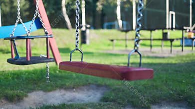 Children&#x27;s swings hang empty an idle at a playground on a dull.