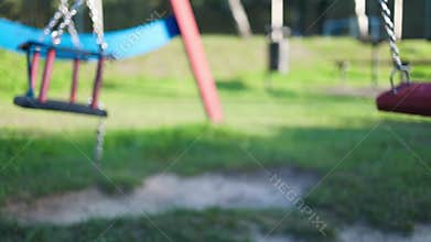 Children&#x27;s swings hang empty an idle at a playground on a dull.