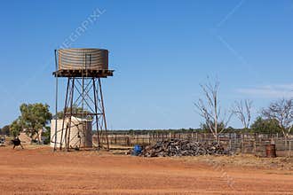 Water tanks, a wood pile and paddocks in a farm yard in Outback country, Australia.