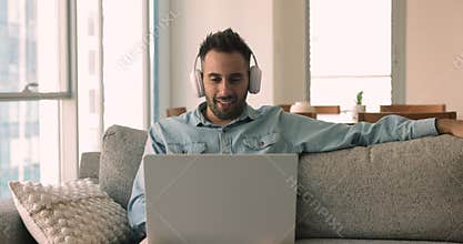 Smiling Hispanic single man having video call talk using laptop