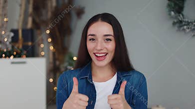 Joyful woman gives thumbs-up in festive kitchen, ideal for holiday ads.