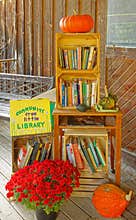 community free little library with books and Fall pumpkins and Chrysanthemums