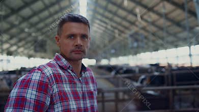 Rancher standing modern cowshed looking camera close up. Portrait farm employee.