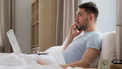 man with folder calling on phone in bed at home