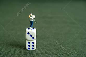 Miniature people toy figure photography. Gambling play concept. A men golfer standing above dice stack