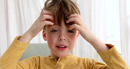 Confused boy touches long bangs with hands looking in camera