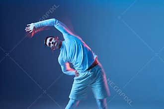 Sportsman doing warm up before workout. Man in white sportswear on blue background does tilt to the left side.