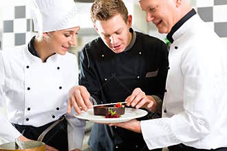 Chef team in restaurant kitchen with dessert