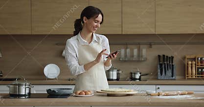 Woman read recipe on cellphone while cook pizza at home