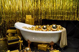 Bathtub full of golden balls. Vintage bright bathroom decorated with festive golden balls. New Year, Christmas bathroom