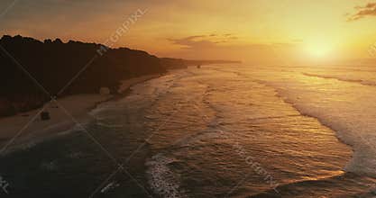 Aerial rolling waves tropical sandy beach at sun set. Slow motion ocean wave. Exotic rocky coast.