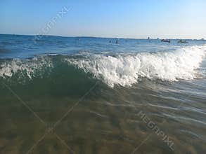 Sea wave with foam and sun glare