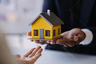 House model with real estate agent and customer discussing for contract to buy house, insurance or loan real estate background