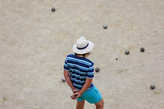 petanque player with white hat in the bowling alley in summer