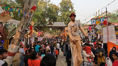 A busy fairground and Stilts walker in fair of Faridabad, India.