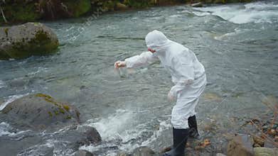 a biologist in a protective white jumpsuit tests the water quality in the river wide view