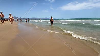Alicante, Spain - May 18, 2025: Relaxing beach day with families enjoying the sun, sand, and waves near the shore in