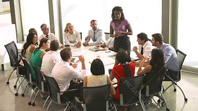 Businesswoman Addressing Meeting Around Boardroom Table