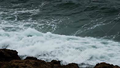 Dramatic Ocean Wave Crashing Against Dark Rocks with Foamy White Crests