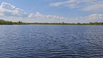 Tranquil lake landscape with blue water and cloudy sky in summer countryside,