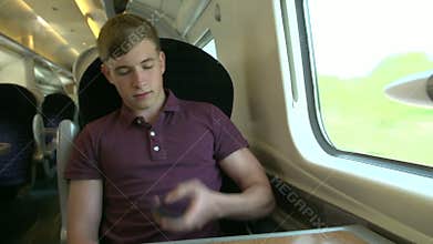 Young Man Using Mobile Phone On Train Journey