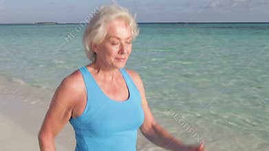 Senior Woman Walking On Beautiful Beach