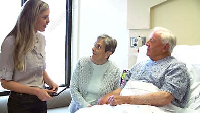 Consultant Talking To Senior Couple In Hospital Room