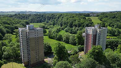 Scenic drone footage of Berry Brow High Rise Flats, between green plants in West Yorkshire