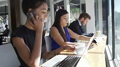 Businesswoman Using Laptop And Mobile Phone In Coffee Shop