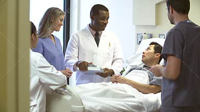 Medical Team Meeting Around Male Patient In Hospital Room