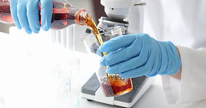 Scientist pours carbonated drink from plastic bottle into beaker