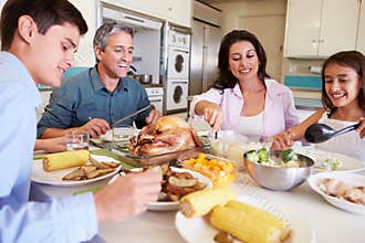 Family Sitting Around Table At Home Eating Meal