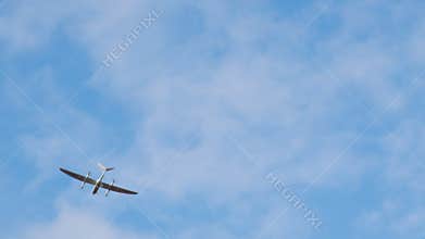 Aerial view of a sleek drone with dual wings and propellers soaring through a clear sky, showcasing advanced technology
