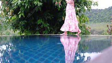 Graceful woman carefully walk on the edge of swimming pool