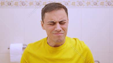 Man suffering from stomach ache while sitting on toilet
