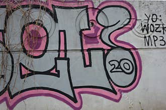 A drawing, graffiti depicting word RUSEL ! is painted on a white-gray concrete fence.