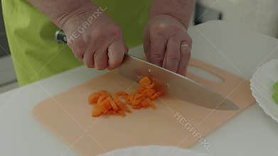 Chef slicing carrots on cutting board