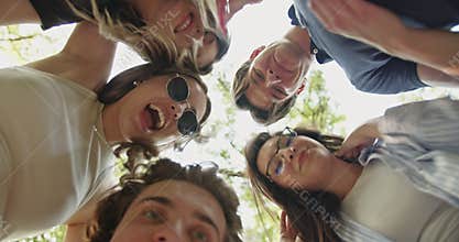 Happy Carefree Friends Look Down and Smile Together in a Joyful Outdoor Gathering.
