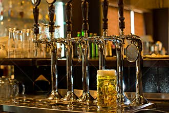 Tankard of beer with beer taps in a pub