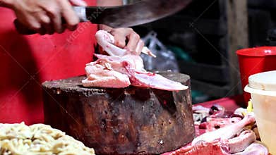 Chicken trader at a traditional market, cutting and cleaning the chicken