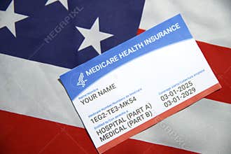 Close up of Medicare health insurance card with dummy information showing on the American flag in the backdrop