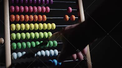 A man counts on a wooden abacus. A wooden abacus with colorful beads on it