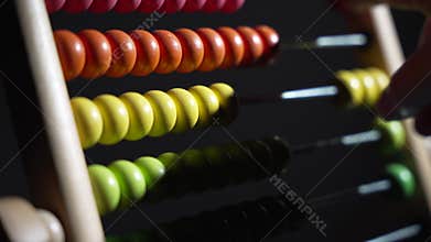 A man counts on a wooden abacus. A wooden abacus with colored beads on it